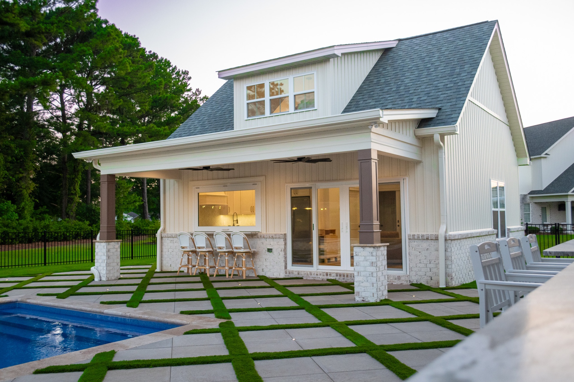 Pool house with covered porch, bar seating, and grass-grid pavers