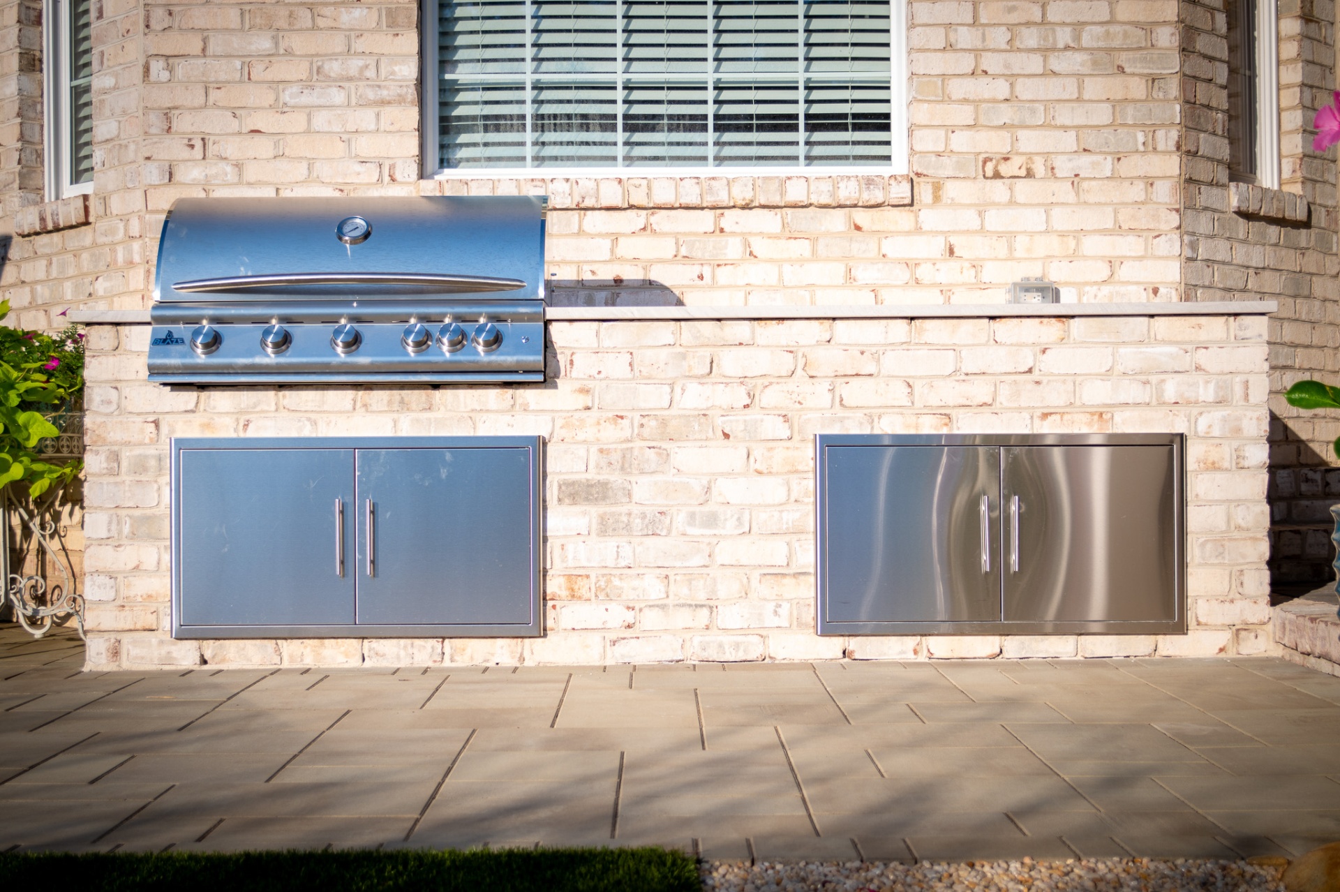 Built-in Blaze grill with stainless cabinetry in whitewashed brick surround