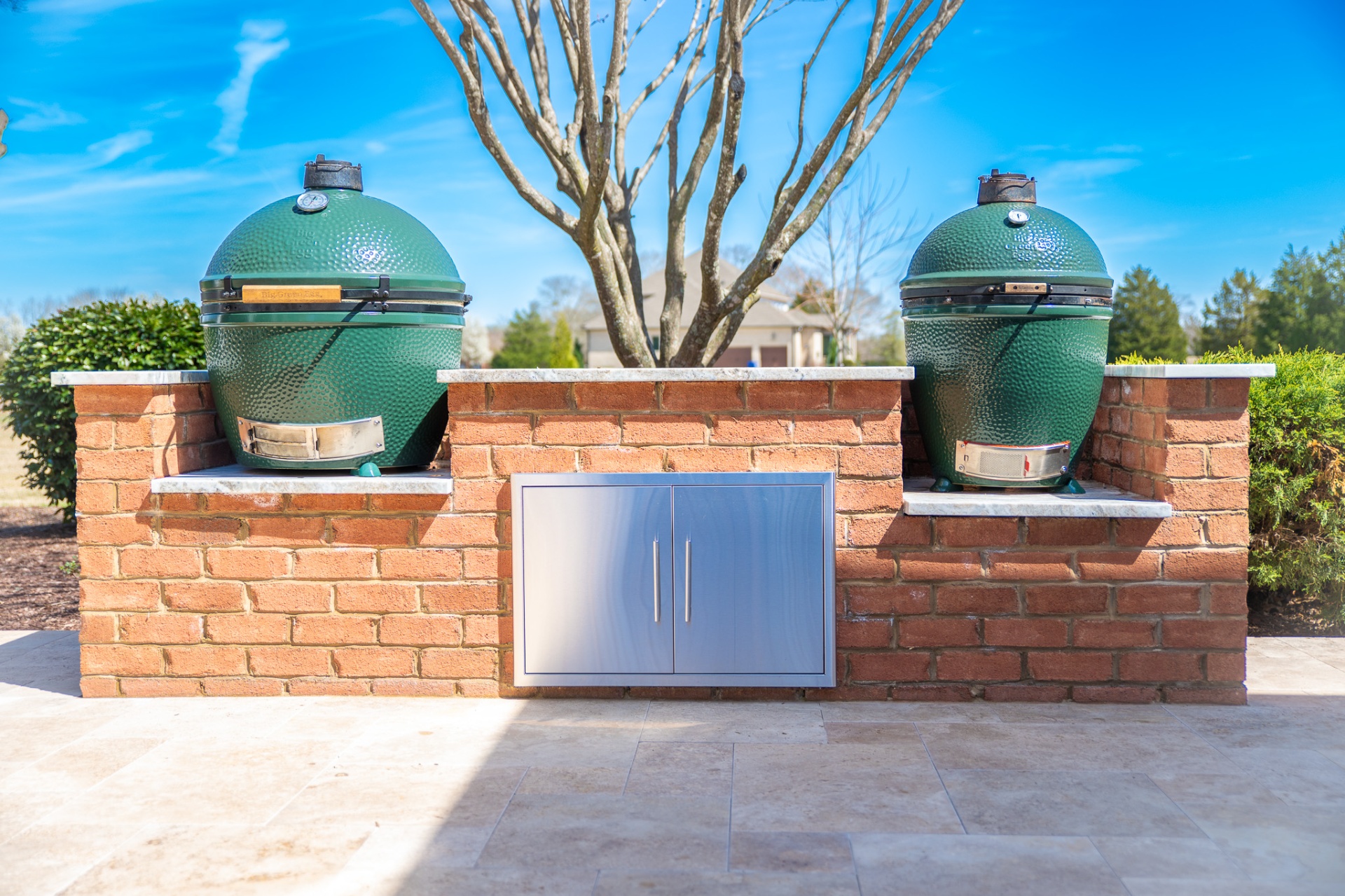 Dual Big Green Egg grills built into brick outdoor kitchen