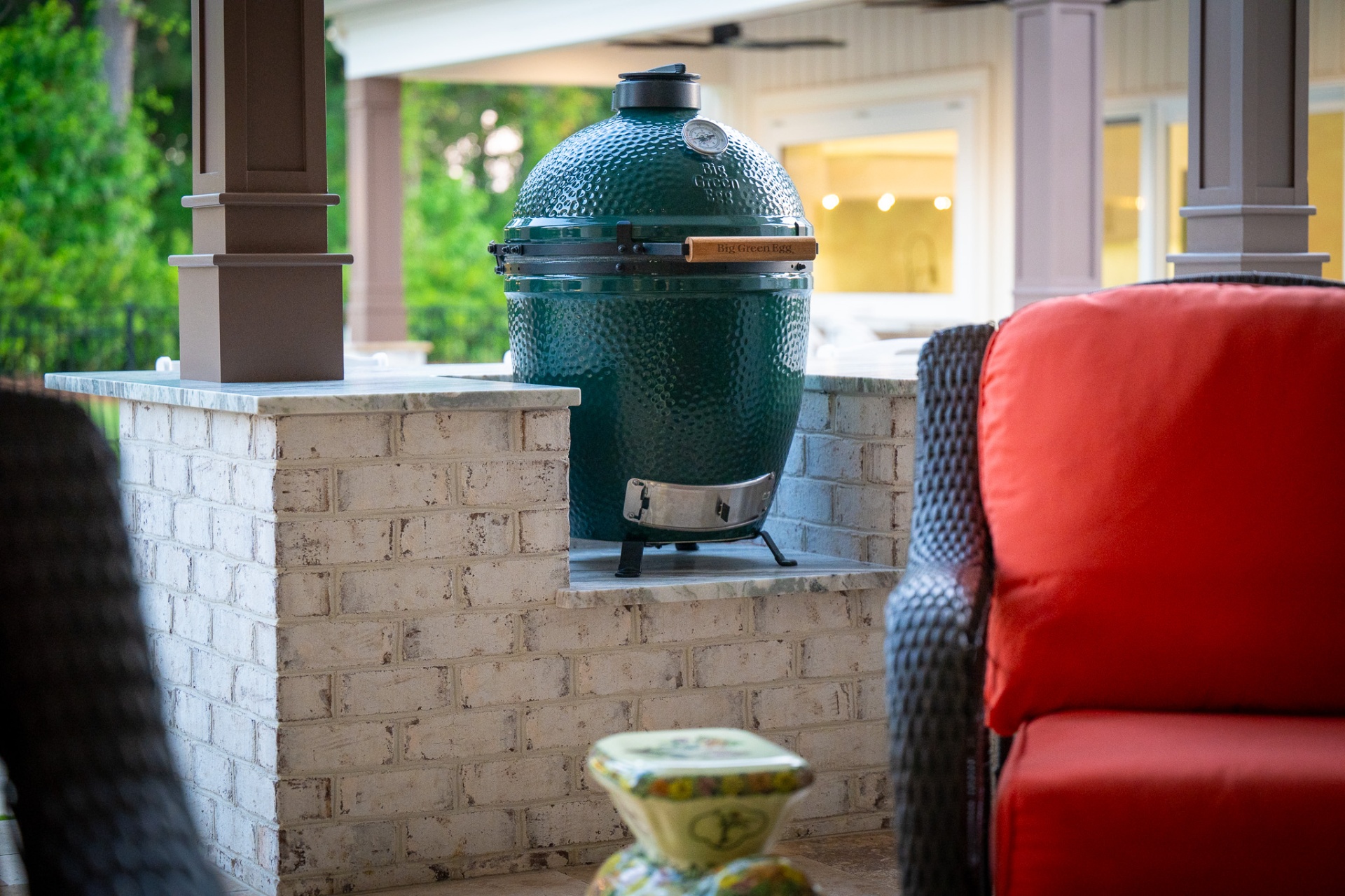 Big Green Egg on brick counter with marble top on covered patio