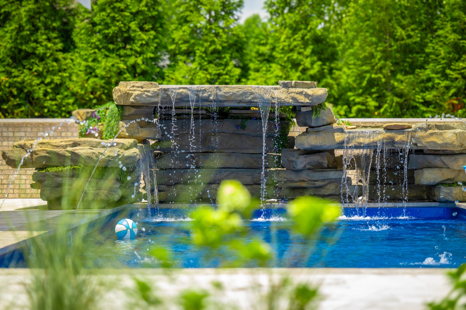 Pool waterfall with beach ball and lush landscaping