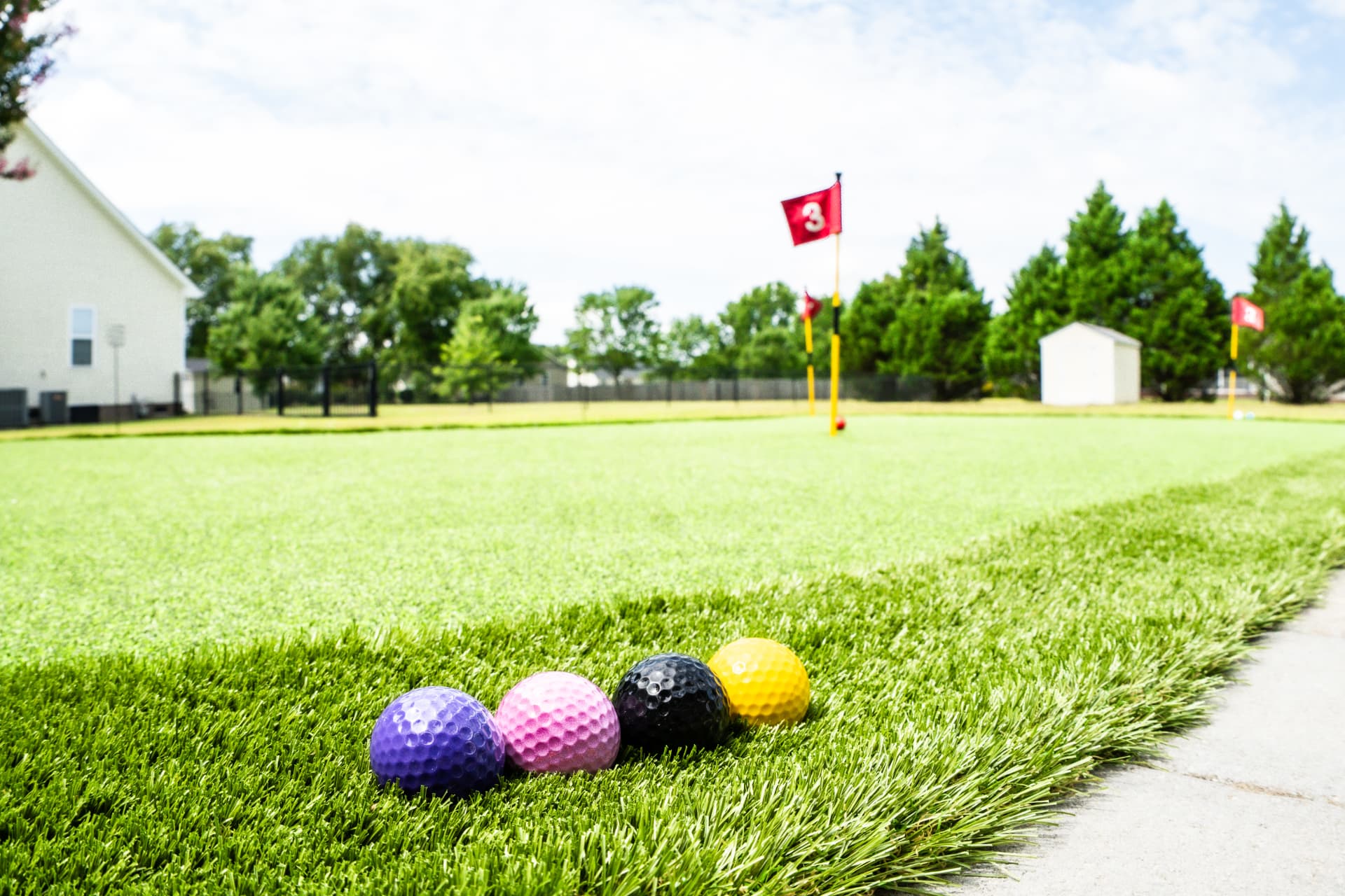Backyard synthetic putting green with numbered flags and colored golf balls