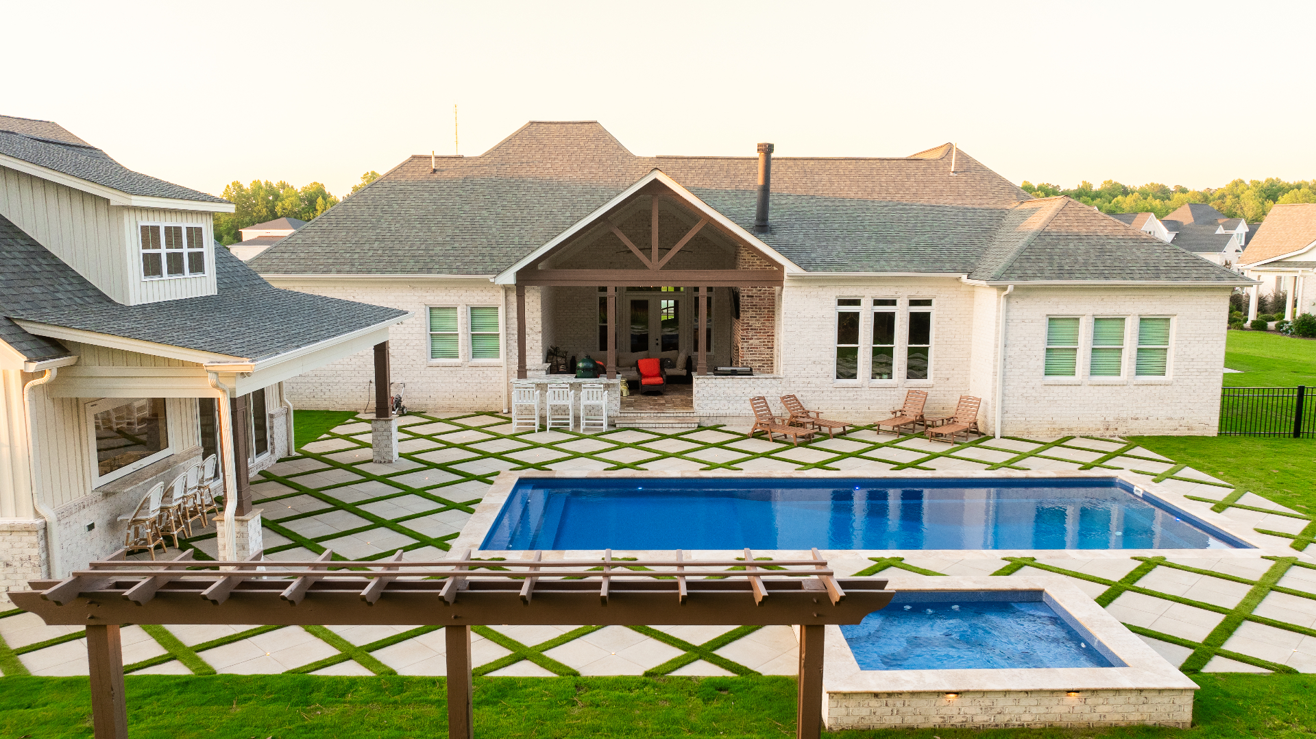 Backyard pool and spa with grass-grid paver patio at sunset