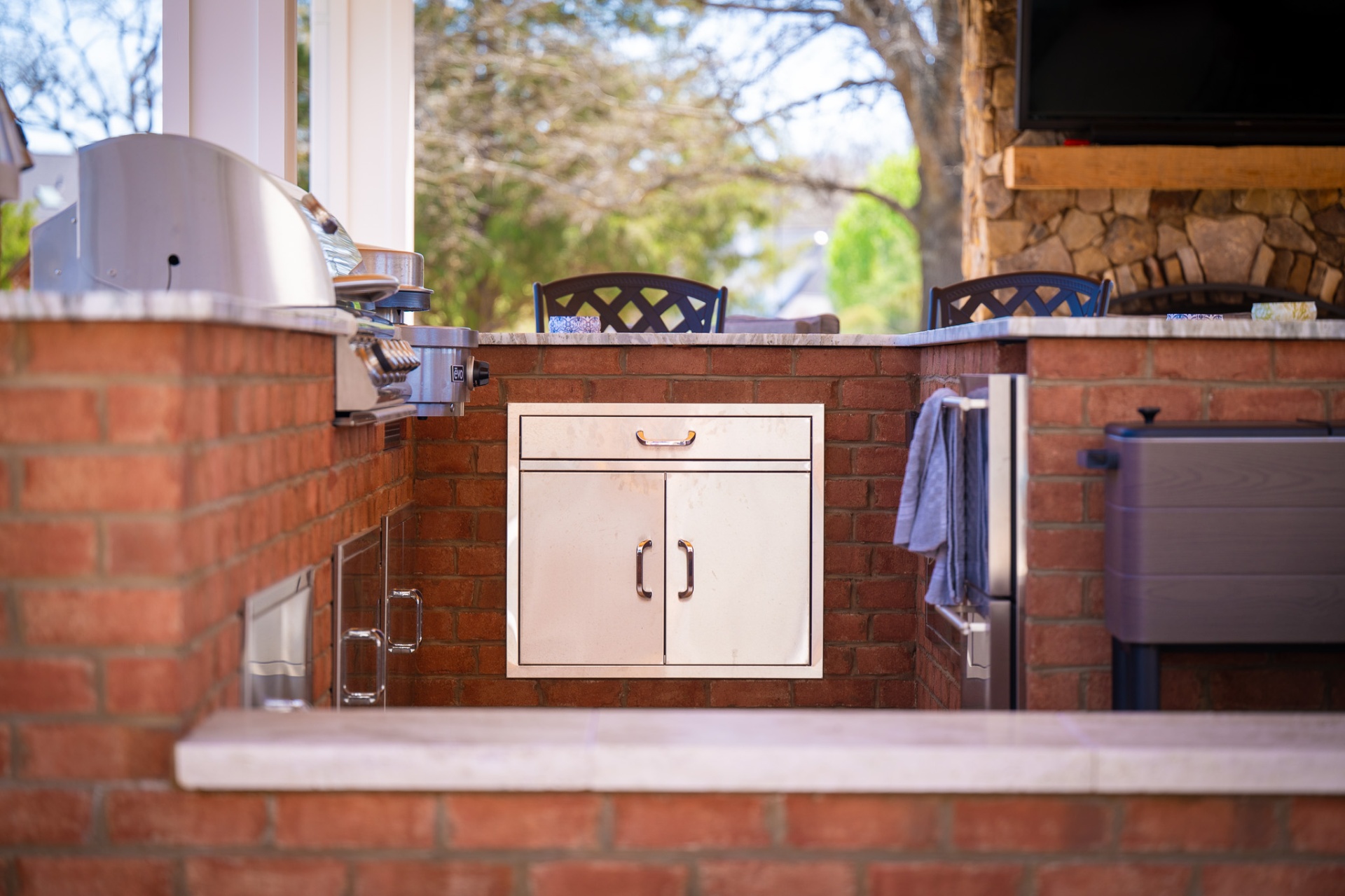 Built-in grill station with stainless cabinetry in brick outdoor kitchen