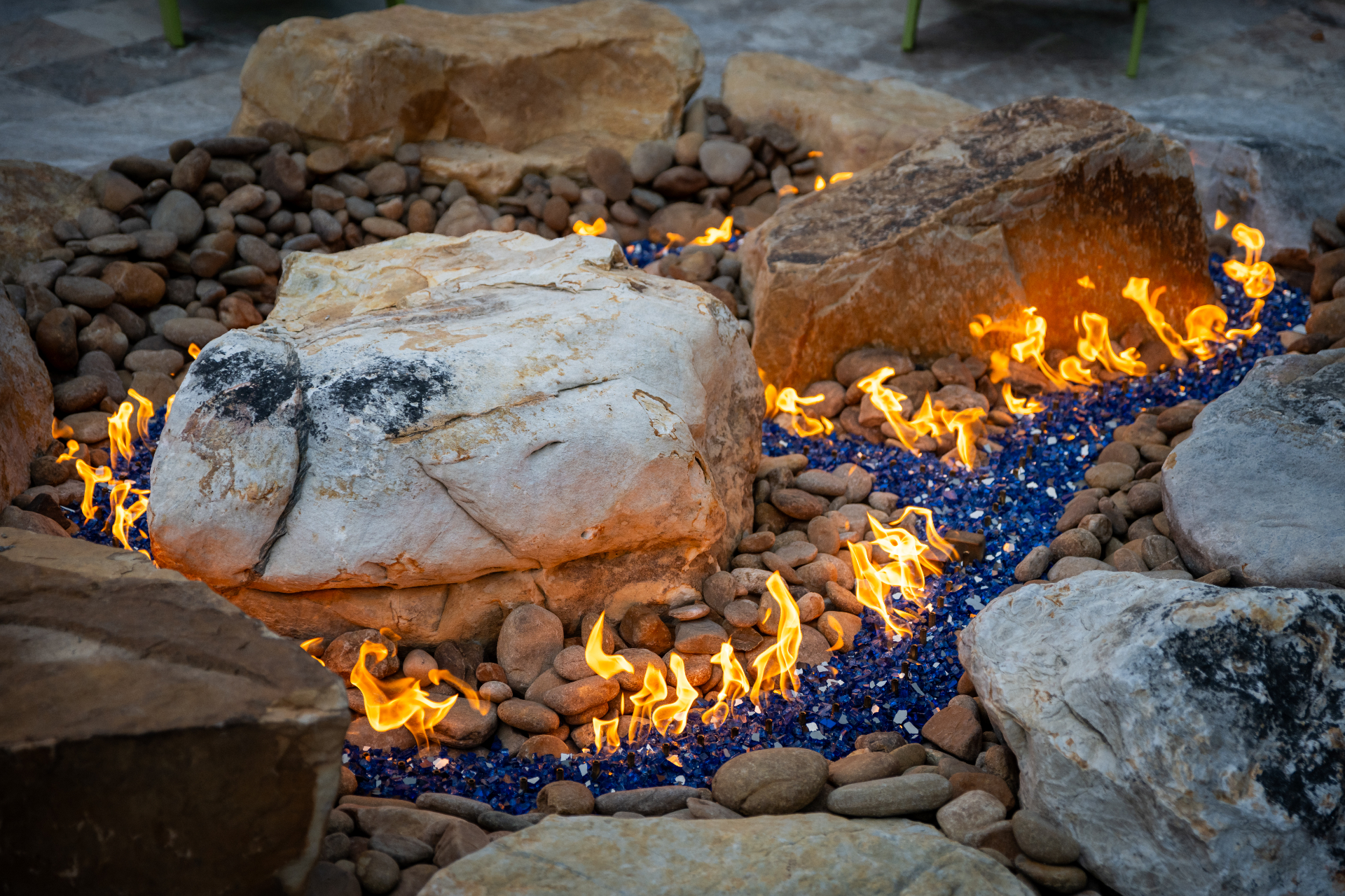 Fire pit with blue glass, river rock, and stone boulders